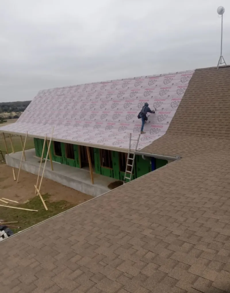 Worker preparing underlayment for a metal roof installation in Sunnyside